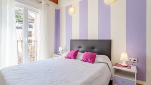 A bedroom with a bed, two nightstands, a window with curtains, and a view of buildings outside. - Apartment 'La Torre' with Wi-Fi and Air Conditioning (Alicante (Alacant))