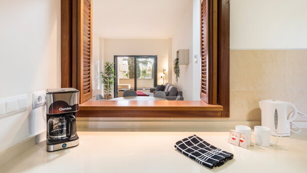 Una cucina moderna con una macchina da caffè, un bollitore e un asciugamano sul bancone.