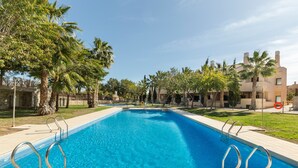 Una piscina con ringhiere metalliche, circondata da palme e edifici.
