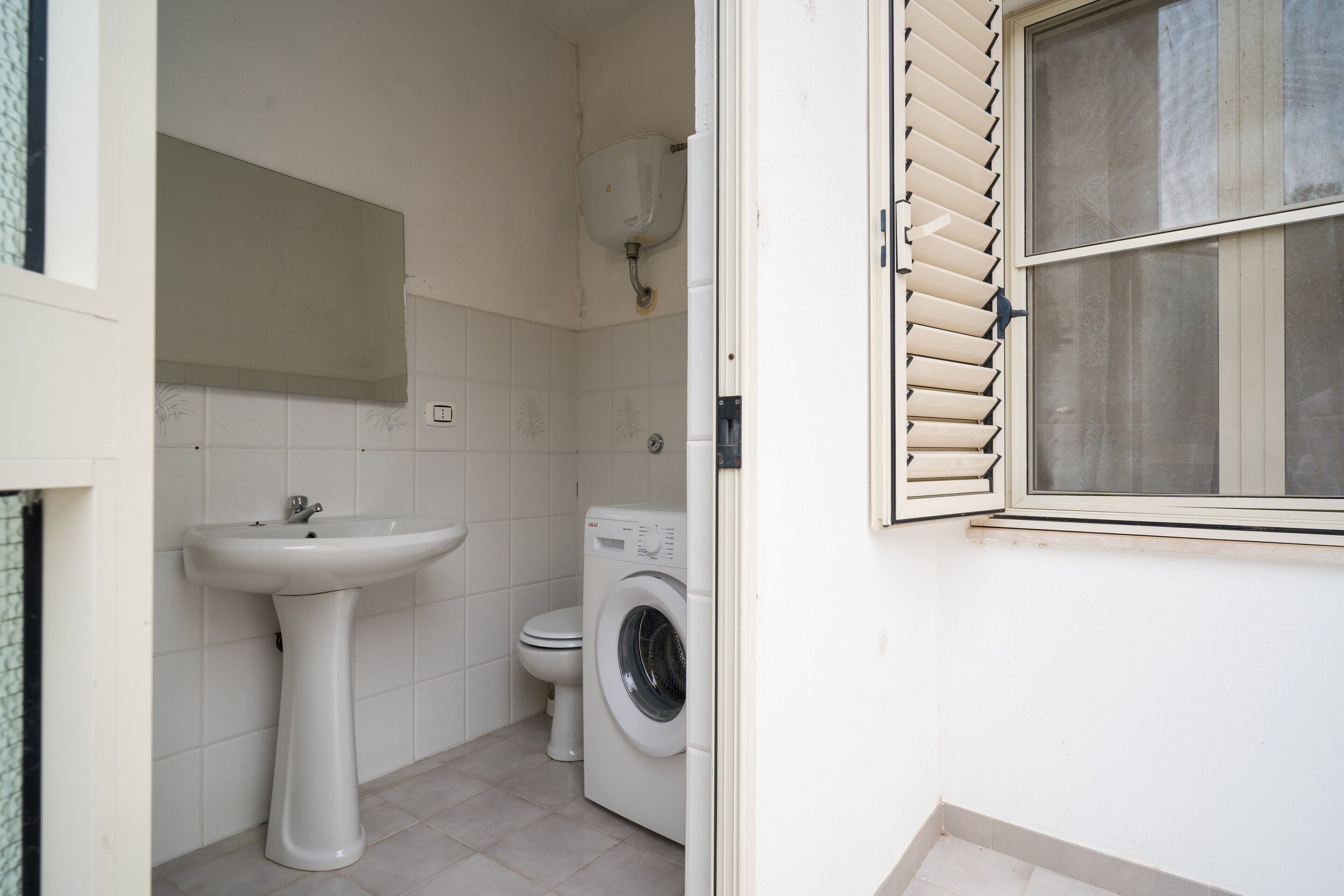 Un baño pequeño y limpio con lavamanos, inodoro y lavadora.
