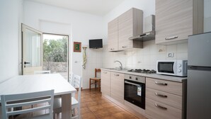 Een moderne keuken met een eethoek, een aan de muur bevestigde televisie en uitzicht op het omliggende landschap.