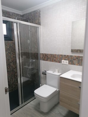 Ein Badezimmer mit Dusche, Toilette und Waschbecken.