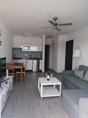 Eine moderne Wohnung mit Essbereich, Küche, Wohnzimmer und Deckenventilator.