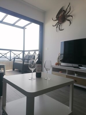 Ein Zimmer mit Fernseher, einer Weinflasche und zwei Gläsern auf einem Tisch.