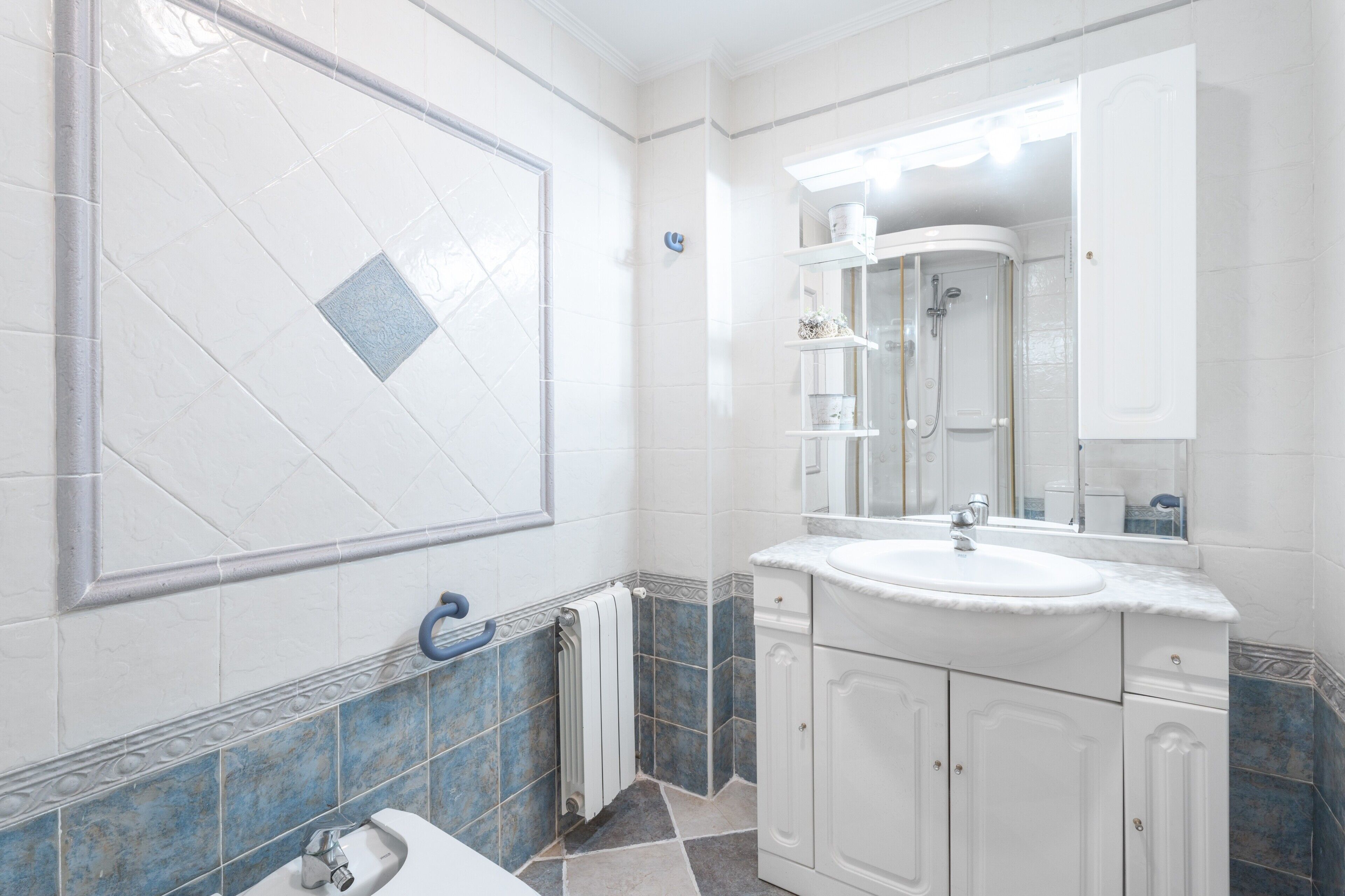 A bathroom with a white sink, mirror, and tiled walls.