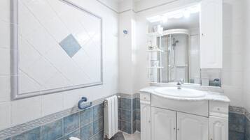 A bathroom with a white sink, mirror, and tiled walls.