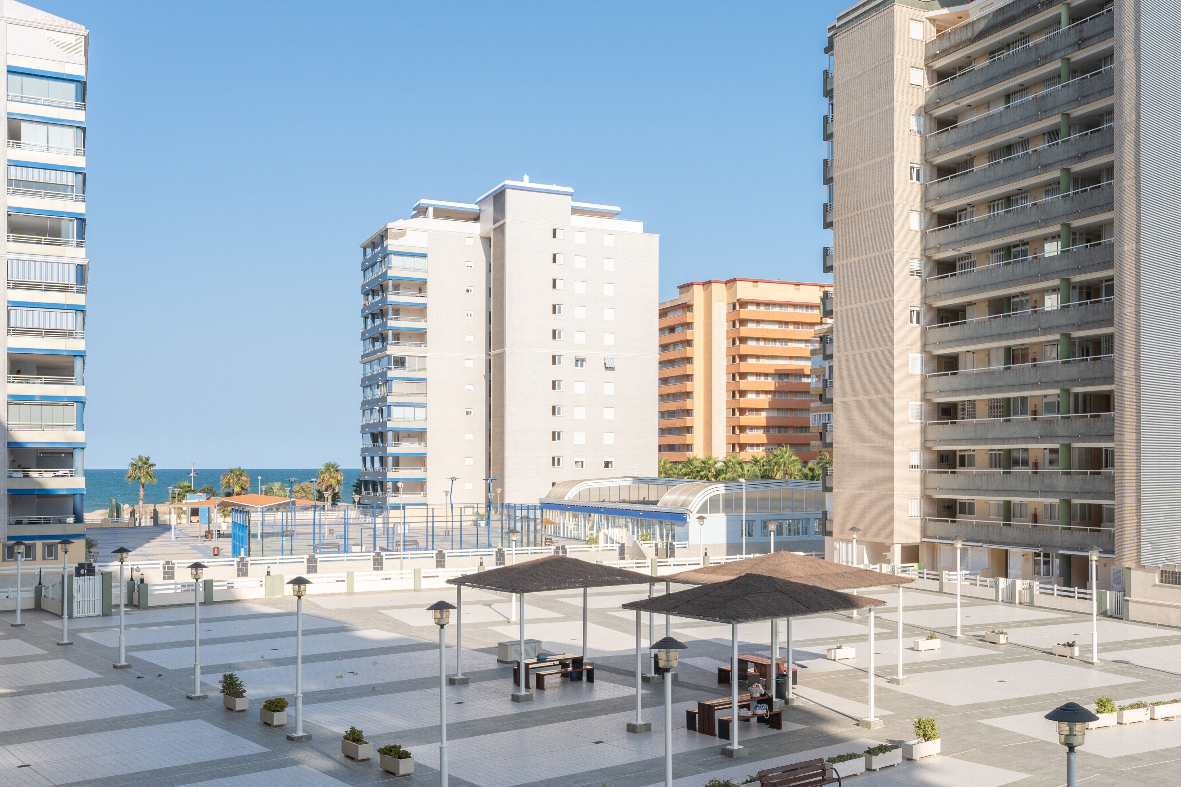 Una piazza moderna in città, con edifici alti, posti a sedere all'aperto e cielo sereno.