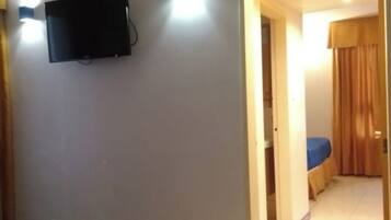 A hotel room with a bed, a television mounted on the wall, and a bathroom visible through an open door.