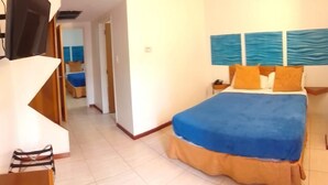 A hotel room with a large bed, a TV, and a view of the sea through the window. - Hotel las Americas (Caracas)
