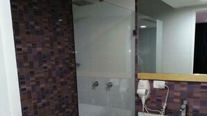 A bathroom with a glass-enclosed shower, a white sink, and a mirror above it. - Hotel las Americas (Caracas)
