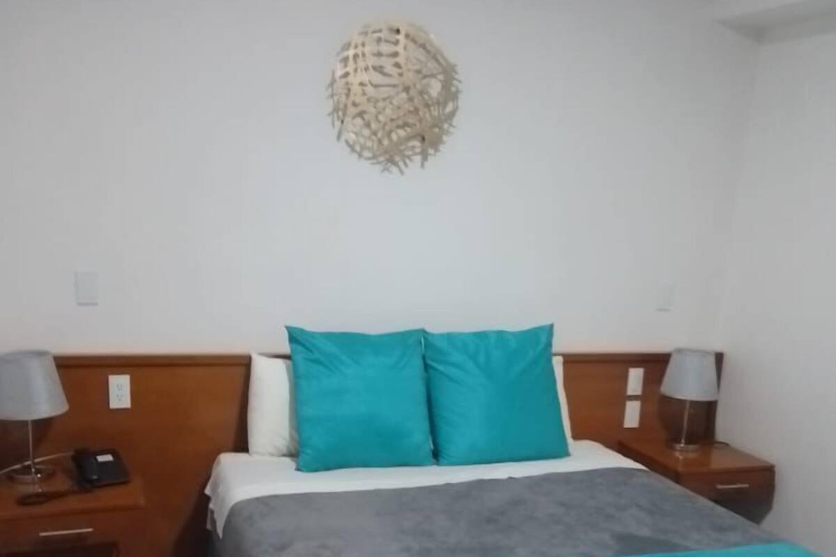 A neatly arranged bedroom with a bed, two bedside tables, and a wall-mounted decorative piece.