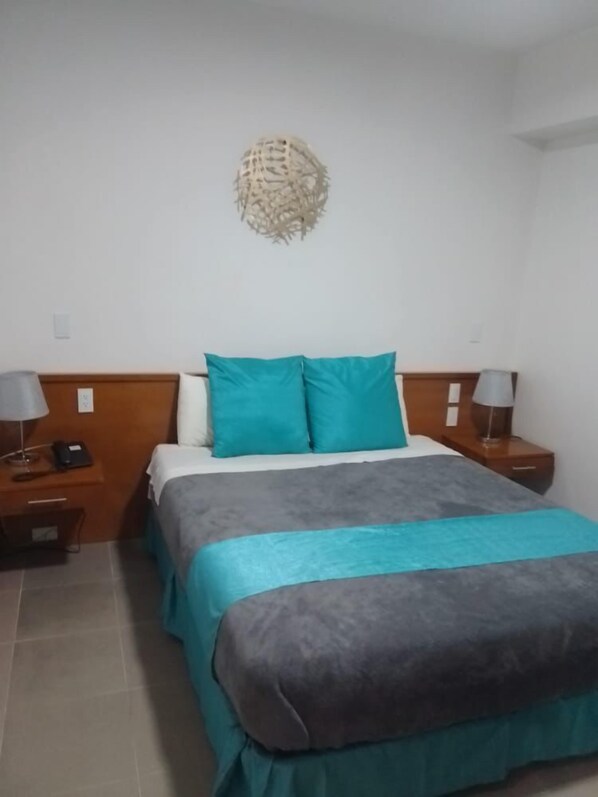 A neatly arranged bedroom with a bed, two bedside tables, and a wall-mounted decorative piece.