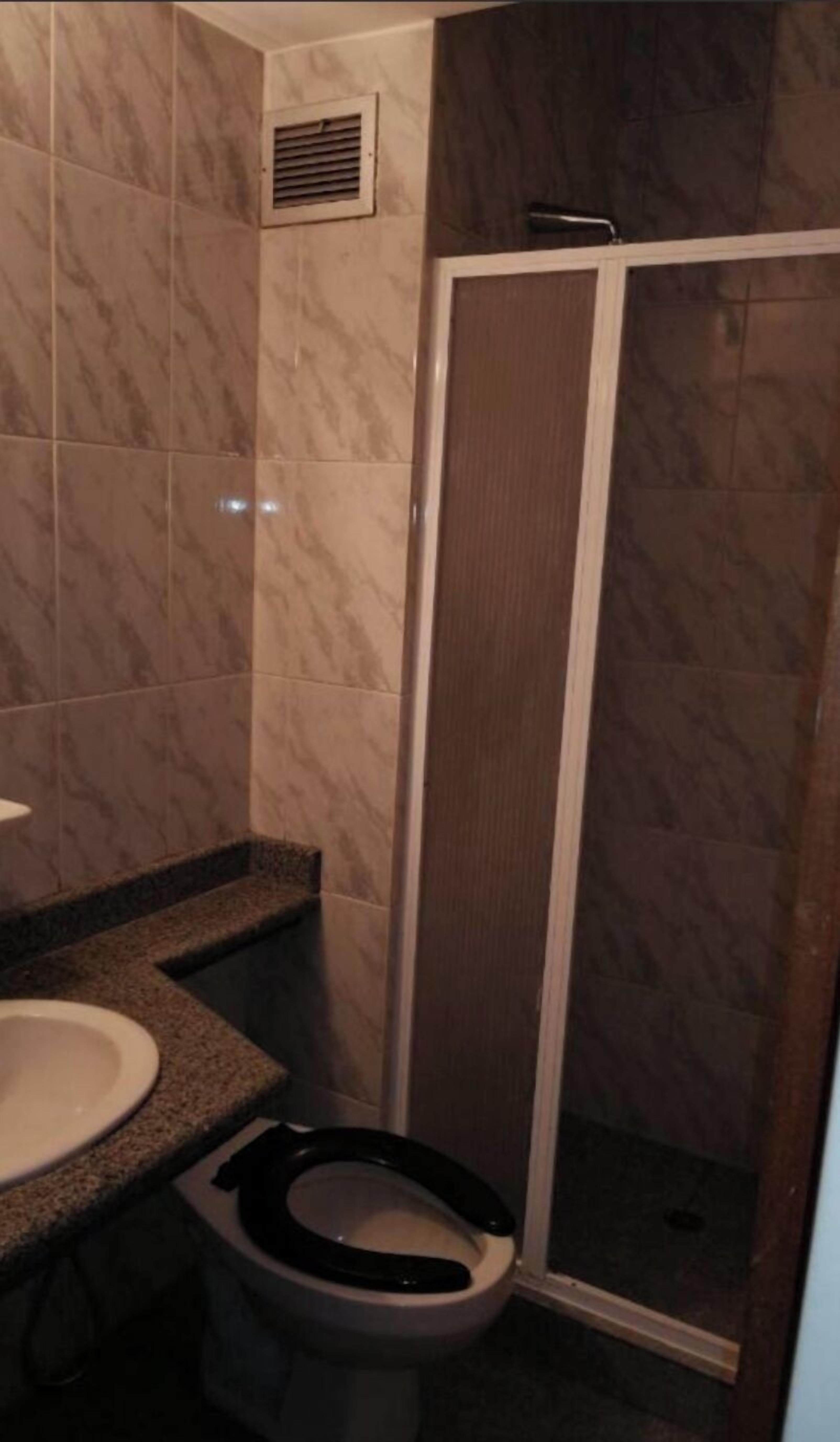 A bathroom with a toilet, sink, and shower area.