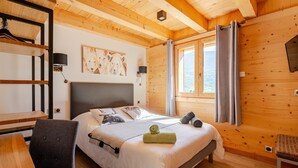 A wooden-paneled room with a bed, a desk, and a chair.