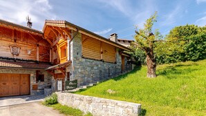 A wooden log cabin with stone walls, a stone staircase, and a sign reading 'Chalet Helvetia.'