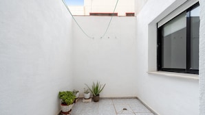 A small enclosed space with tiled flooring, a window, and several potted plants.