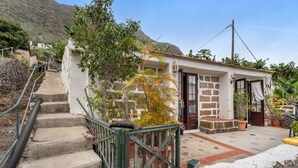 Un bâtiment avec un escalier menant à une porte, entouré de plantes en pot et avec une montagne en arrière-plan.