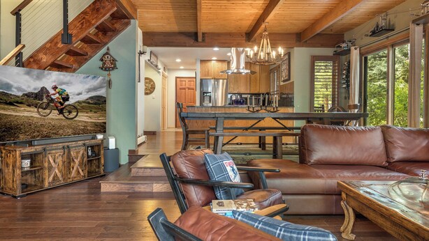 A spacious living area with leather furniture, a wooden staircase, and a kitchen in the background. - Private Hot Tub & Pet Friendly + Beds For Any Group Dynamic (Avon)