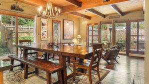 A spacious dining area with a large wooden table, benches, and chairs. There is a chandelier above the table, and the room has large windows and doors leading to an outdoor patio. - Private Hot Tub & Pet Friendly + Beds For Any Group Dynamic (Avon)