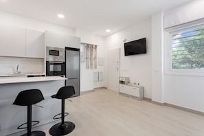 A modern kitchen with a microwave, oven, and bar stools.