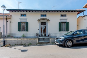A two-story building with a central entrance, a small porch, and a car parked in front. - Holiday Home 'House of Flowers' with Balcony and Wi-Fi (Montopoli vald’arno)