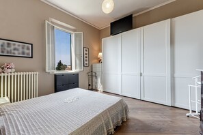 A bedroom with a bed, a wardrobe, a radiator, a window, and a TV. - Holiday Home 'House of Flowers' with Balcony and Wi-Fi (Montopoli vald’arno)