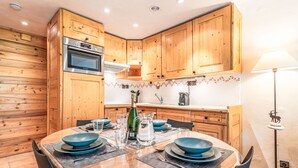 A modern kitchen with wooden cabinets, a Bosch oven, and a dining table set with blue plates and glasses.
