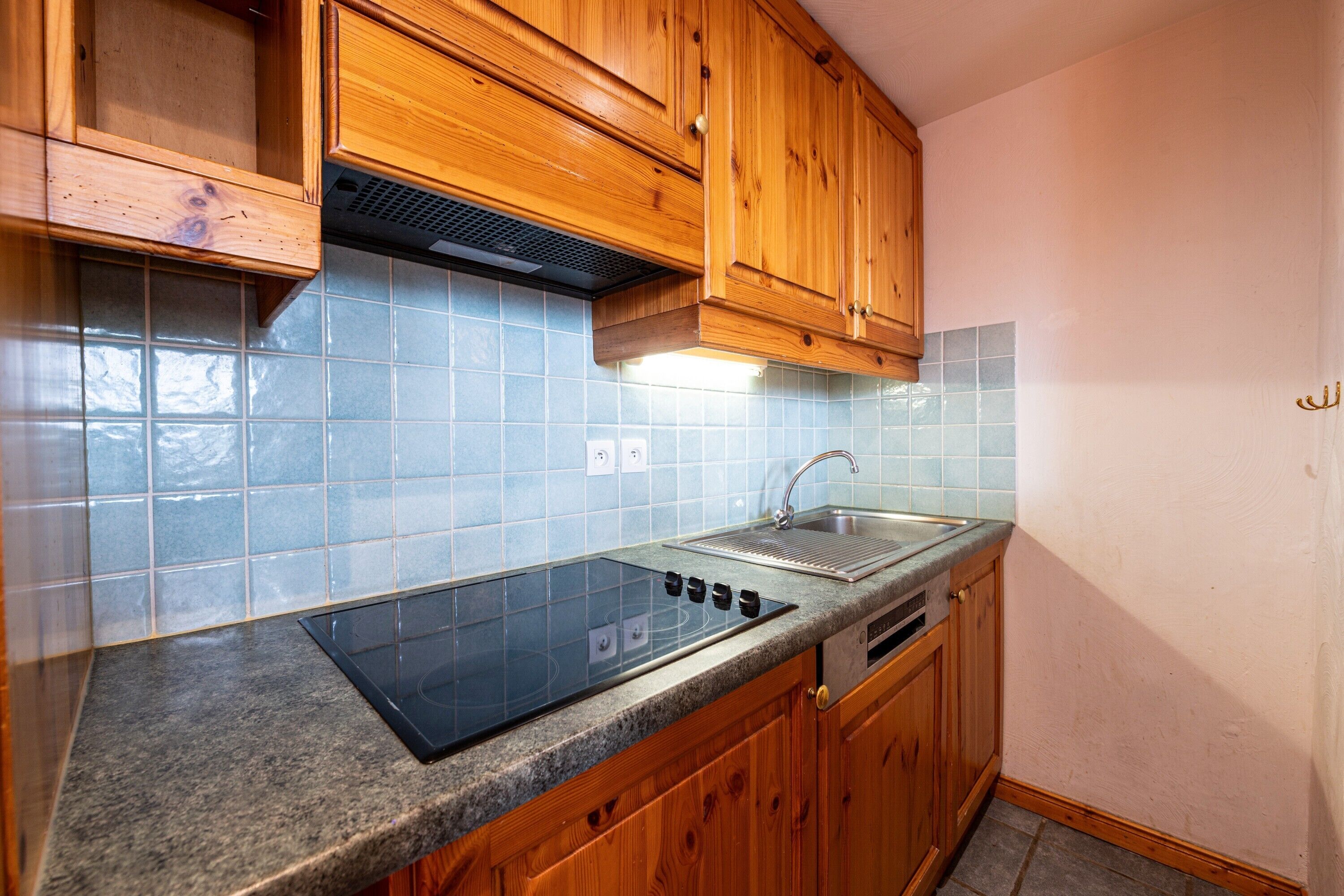 Una cocina con armarios de madera, estufa integrada y salpicadero de azulejos.