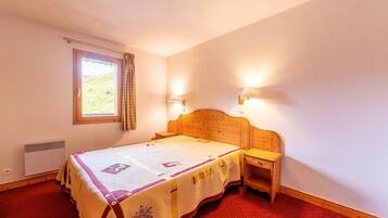 A bedroom with a wooden bed, a window with a curtain, two bedside lamps, and a red carpet.