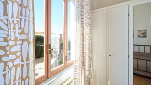 Ein Zimmer mit großem Fenster, einer Tür mit dekorativer Verkleidung und einem Etagenbett.