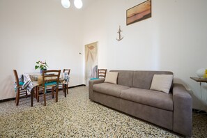 Un salon comprenant un canapé, une table à manger, des chaises et un élément décoratif mural.