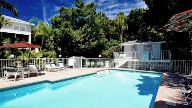 Une piscine avec des chaises longues et un petit bâtiment en arrière-plan.
