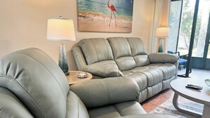 Una sala de estar moderna con un sofá modular, una mesa de centro redonda y un cuadro con una escena de playa.