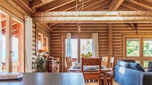 L’intérieur d’une cabane en rondins comprend un coin repas, un canapé et un comptoir de cuisine.