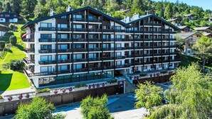 Un hotel de varios pisos con balcones, ubicado en una zona montañosa con abundante vegetación.