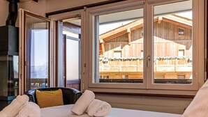 Habitación de hotel con cama, ventana y vista a un edificio de madera exterior.