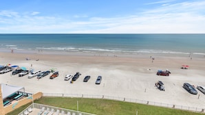 Une plage avec un parking et un bâtiment doté d’une piscine.