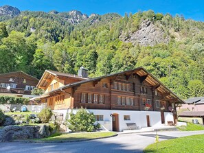 A traditional wooden chalet with a sloped roof, multiple windows, and a stone foundation. - Eisiboden by Interhome (Nessental)