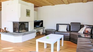 Ein modernes Wohnzimmer mit Kamin, Fernseher, Sofa und Couchtisch.