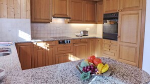 Eine Küche mit Holzausstattung, einer Arbeitsplatte aus Granit und einer Obstschale.