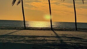 A beach scene with palm trees and the sun setting over the ocean. - FOUND! Million Dollar View! Stunning Fort Meyers Beach Condo! Book Early & Save! (Fort Myers Beach)