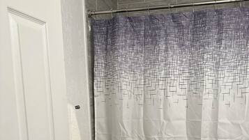 Ein Badezimmer mit einer weißen Tür, einem Duschvorhang mit geometrischem Muster und einer Toilette.