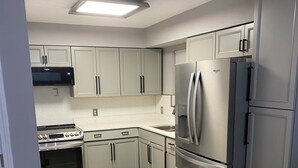 Una cocina moderna con electrodomésticos de acero inoxidable, armarios de color gris claro y salpicadero con patrón de espiga.