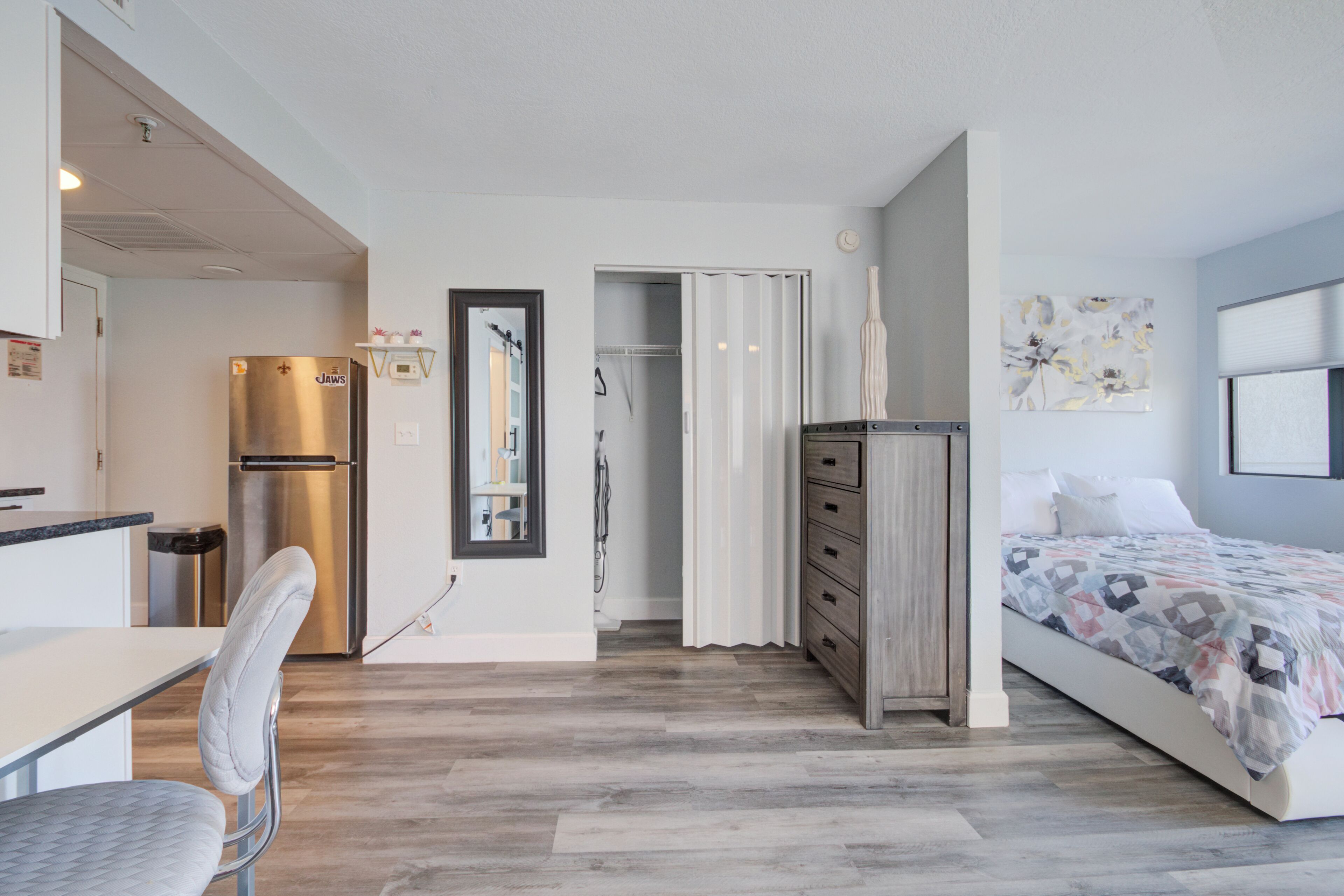 Une chambre à coucher moderne, avec un lit, une commode, un miroir et une porte donnant sur une salle de bain.