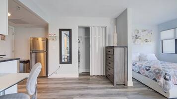 Une chambre à coucher moderne, avec un lit, une commode, un miroir et une porte donnant sur une salle de bain.