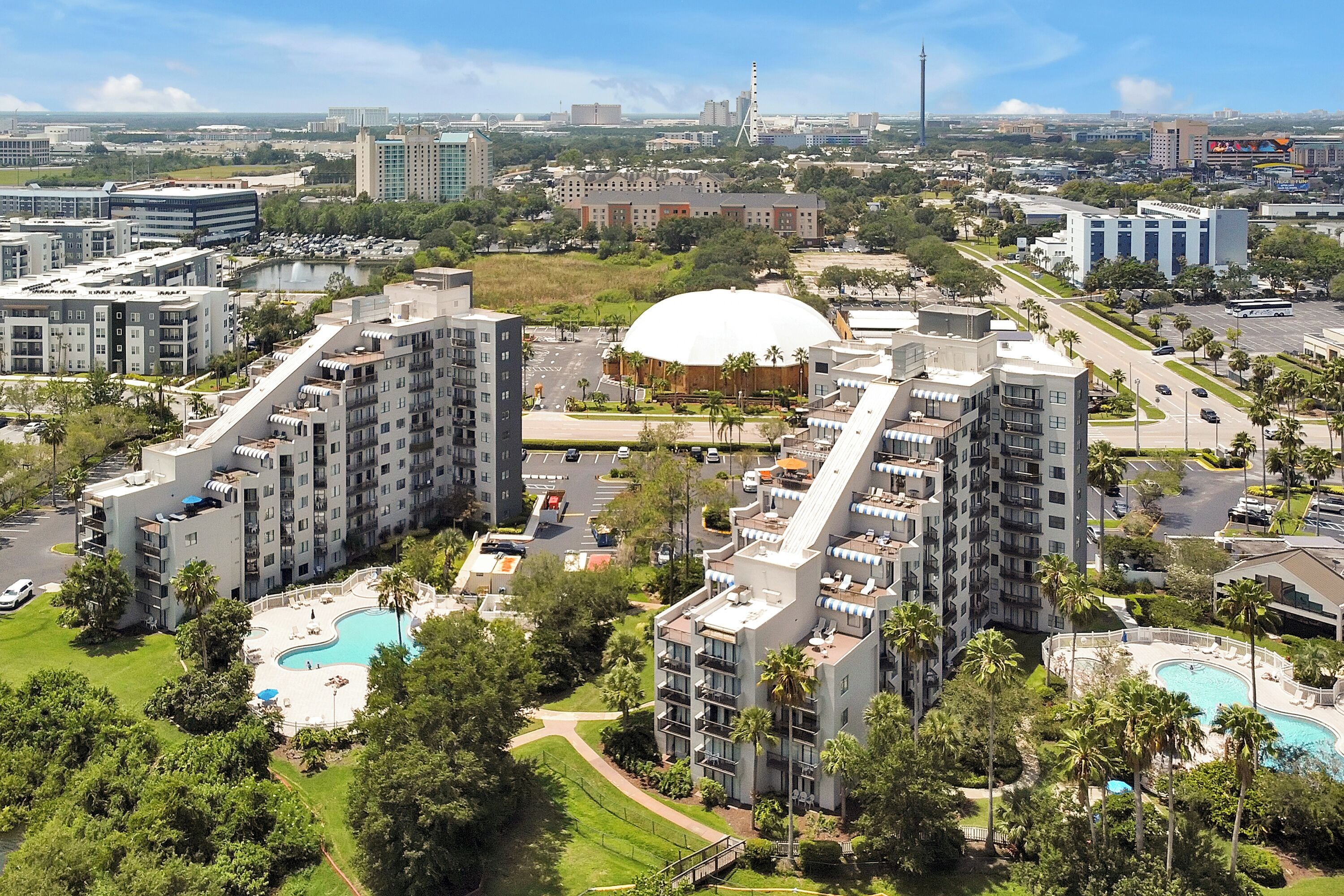 A high-rise hotel with multiple balconies, a central courtyard with a swimming pool, and a large dome structure.