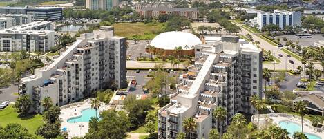A high-rise hotel with multiple balconies, a central courtyard with a swimming pool, and a large dome structure.