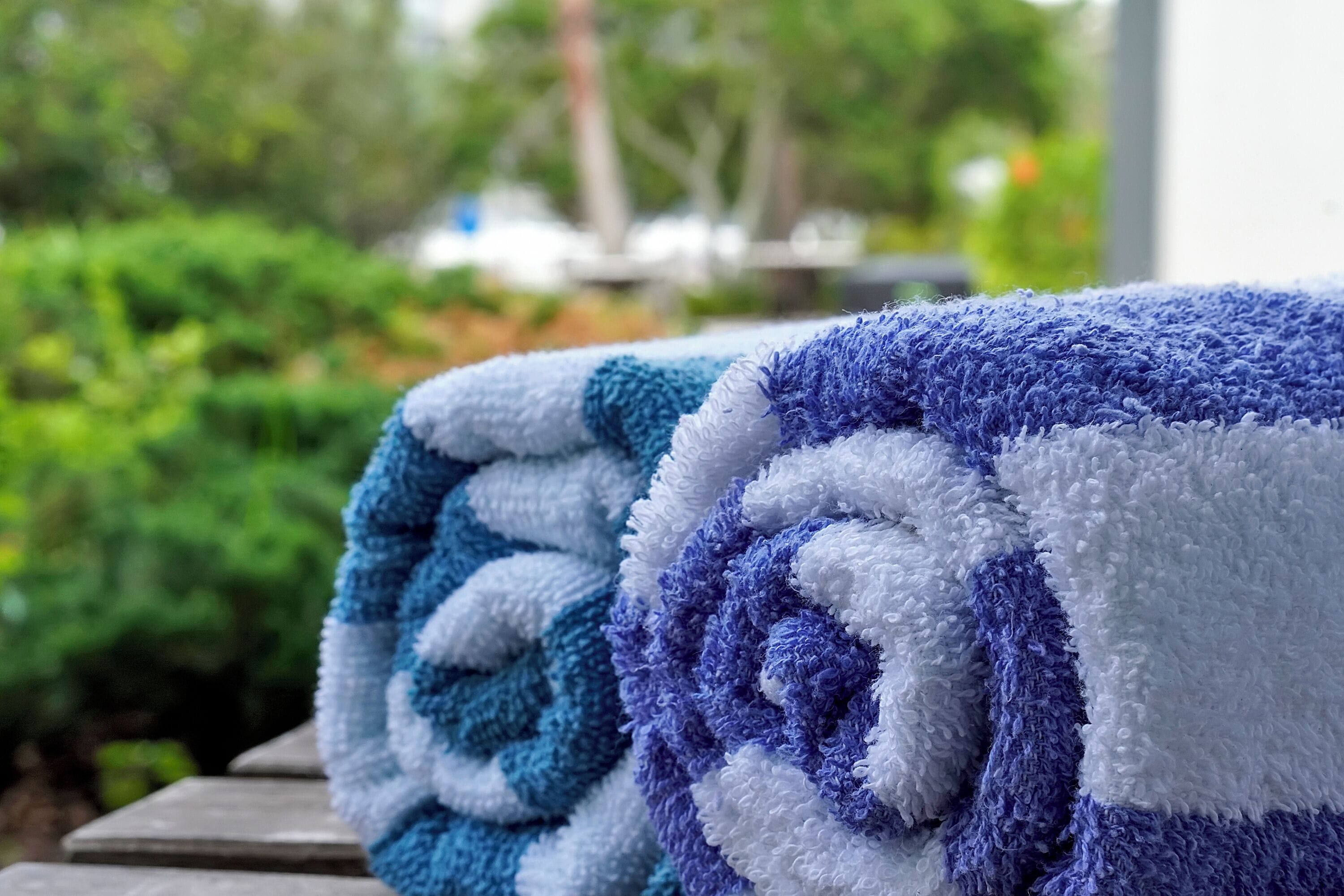 A close-up of a folded towel with a blue and white pattern, placed outdoors with greenery in the background.