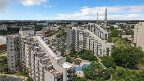 A high-rise residential building with multiple balconies, a rooftop pool, and surrounding greenery. - Premium Condos near Universal Studios (Orlando)