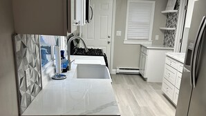 A modern kitchen with a white countertop, a built-in stove, and a refrigerator. - Newly Renovated Luxury 2-BD 2-BA house, AC, WiFi. Mins to NYC, EWR, Newark Distr (Union)